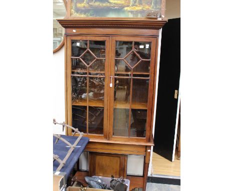 An Edwardian mahogany display cabinet fitted with two glazed doors over a single panel door, raised on off centre turned legs