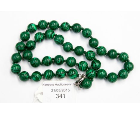 A Malachite single strand bead necklace, with approximately 39 round 10mm beads, each individually knotted, fitted on a white