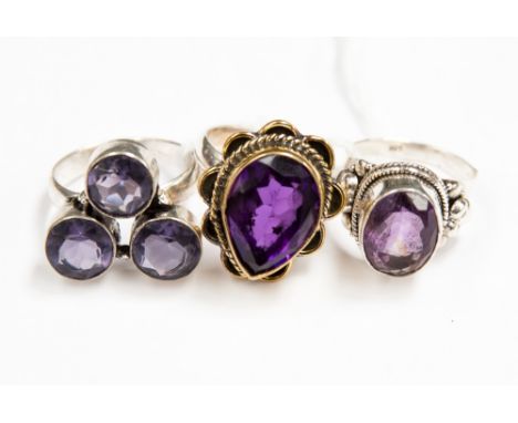 Three silver amethyst ladies dress rings, one set with a cluster of three amethysts, one set with an oval amethyst and anothe