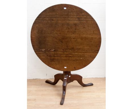 A George III oak tilt top tripod table, the circular top raised on a turned column, raised on cabriole legs circa 1770 