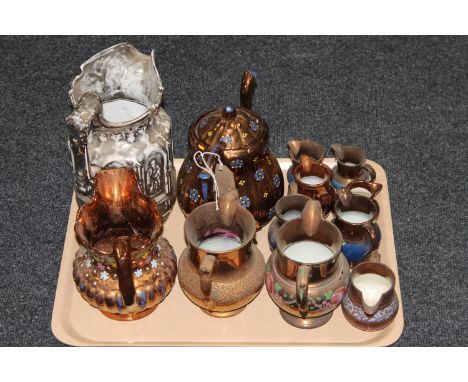 A tray containing eleven copper lustre jugs, together with a copper lustre teapot (12)