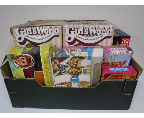 A box containing vintage games and toys, including two Girls Worlds Hair Styling Models, a battery operated sewing machine, a