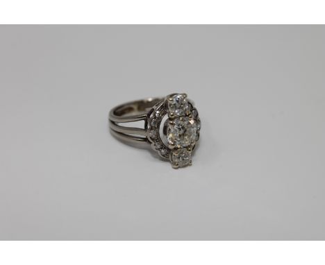 A platinum and diamond ring, the three old cut diamonds in raised claw settings above a diamond border, the principal diamond