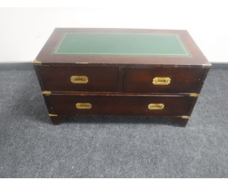 A campaign style three drawer chest with brass mounts and leather inset panel 