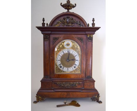 A late Victorian walnut and gilt metal mantel clock, the arched case with urn finial above a gilt face with silvered chapteri