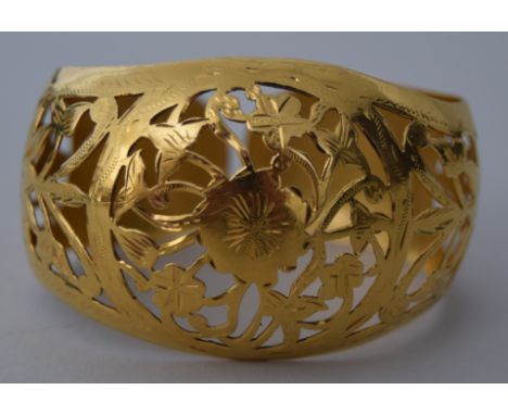 A yellow metal bangle, early 20th century, probably Indian, with pierced foliate decoration, 5.5cmD