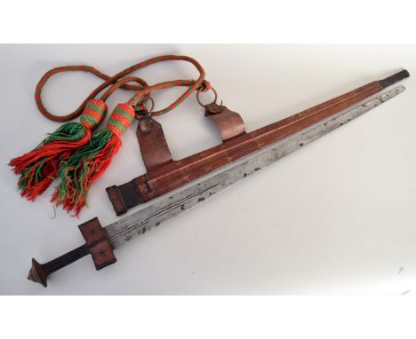 A sword with leather and metal hilt complete with a leather scabbard and ornamental red and green shoulder rope with tassels,