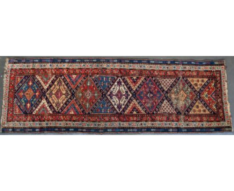 A Caucasian runner, early 20th century, with a chain of six and a half hooked lozenges containing floral motifs within foliat
