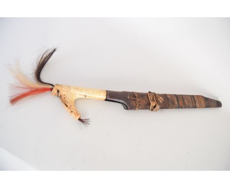 A Southeast Asian sword, possibly from Indonesia or Borneo, with bone/ivory hilt featuring red white and black plume and engr