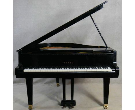 A Yamaha G1 grand piano in black gloss lacquered case on brass roller castors, serial number 2083203 with maker's marks. H.3'
