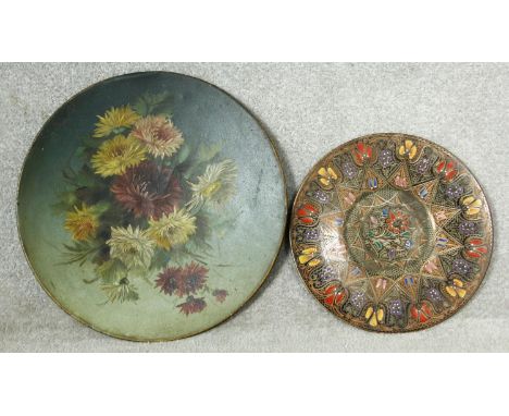 A large 19th century hand decorated oil on metal floral wall hanging display dish and an Eastern polychrome enamel on copper 