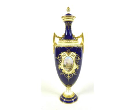 A Coalport twin handled covered vase, cobalt blue ground, overlaid with raised gilding, and a front facing panel painted with