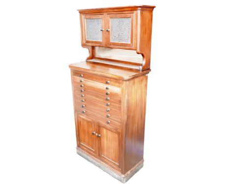 A mid 20th century mahogany dentist's cabinet, with an upper section of twin glazed doors over an open shelf with mirrored ba