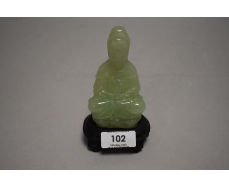 A light green jade or nephrite figure statue of a seated Tibetan Buddha sat on lotus leaf with wooden stand