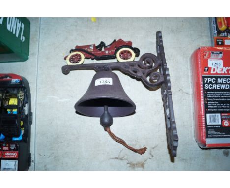 A cast metal bell on bracket decorated with vintage motor car