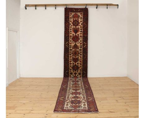 A Persian Heriz wool runner,mid-late 20th century, Iranian, the pale foliate ground woven with repeating geometric medallions