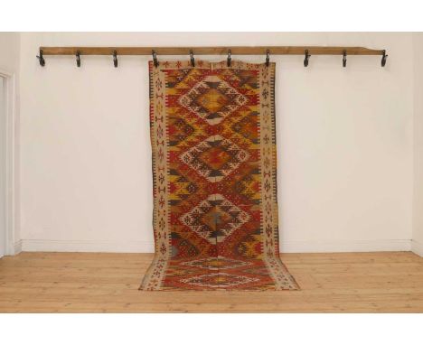 A kilim flatweave wool rug,20th century, the field centred with five geometric medallions,315 x 128cmMuch separation to the c