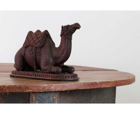 A carved hardwood inkwell in the form of a seated camel,19th century, the saddle lifting to reveal a recess within, on an ova