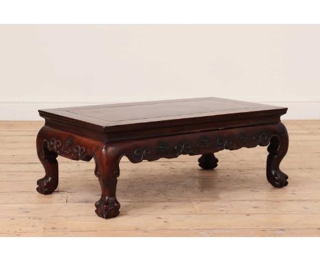 A low opium table,19th century, Chinese, the panel inset top over a shaped apron, carved with scrolls and prunus and raised o