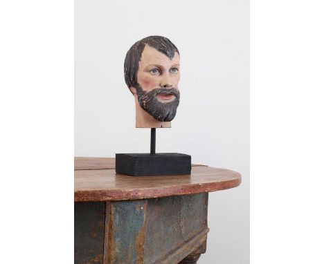 A carved and painted wooden head of a saint,20th century, Spanish, raised on a later stand,32cm high Light chips and wear, sc