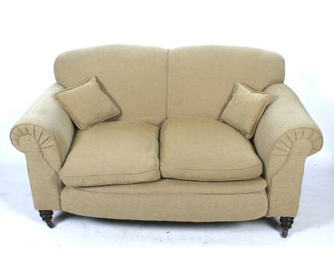 A two seater drop end sofa. Upholstered in light brown fabric, raised on turned supports, on casters, H94cm x W168cm x D90cm