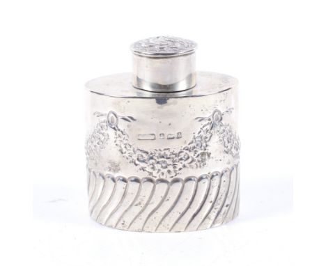 An Edwardian silver oval part-fluted tea caddy. With an unmarked floral embossed pull-off cover, the body embossed with ribbo