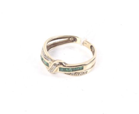 A modern 9ct gold, emerald and diamond cross-over channel ring. The D-section shank with Birmingham convention hallmarks, siz