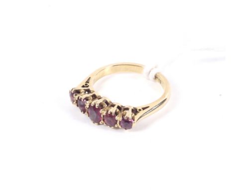 A vintage gold and oval violet-ish paste five stone ring. The graduated pastes claw set on a D-section shank stamped '18ct', 