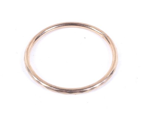 An early 20th century 9ct rose gold faceted hollow round section 'slave' bangle. Hallmarks for Chester 1912, 5mm diameter, in