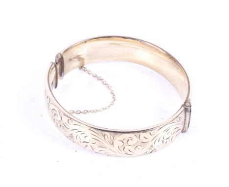 A '1/5th 9ct gold metal core' part foliate engraved hinged broad bangle. 30.4g gross