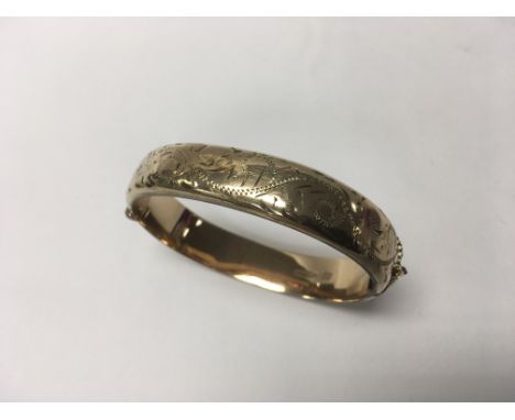 A 9ct gold bangle with metal core and safety chain. Weight approx 19.8g