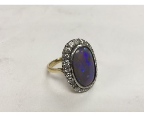 An 18ct gold ring set with a central opal and surrounded by diamond chips (crack to opal), approx 6.3g and size J-K.