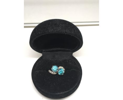 An Edwardian white gold ring with crossover setting of two light acqua sapphires flanked by diamonds.Approx size L/K