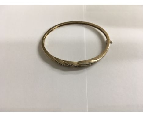 A 9ct gold fancy style diamond set bangle.
