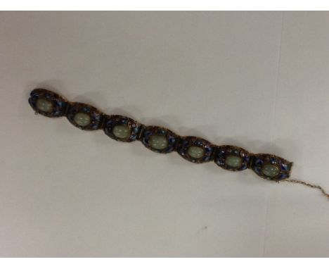 A gold type tone bangle with enamel and jade type stones.