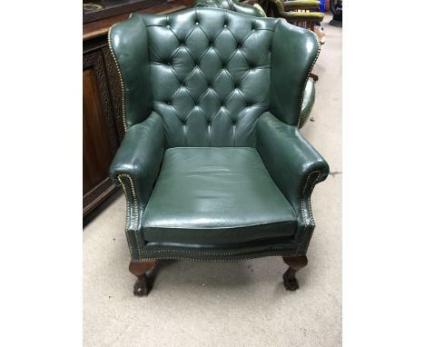 A Quality green leather upholstered wing arm chair with button back and drop in seat on cabriol legs and ball and claw feet. 