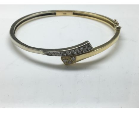 A two tone yellow gold bangle set with diamonds, stamped 18ct. Approx weight 21.7g