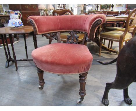 A 19th Century library tub chair with carved scroll splat, deep pink velour upholstery, turned legs to ceramic castors 74cm w