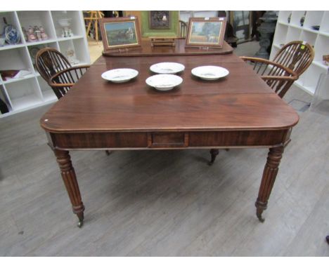 A Georgian mahogany concertina action extending dining table of rounded square form raised upon six melon-fluted legs, with t