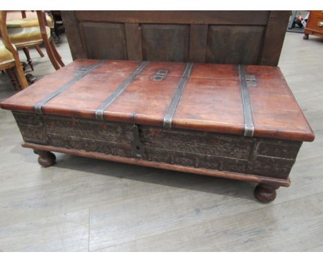 An Indian hardwood coffee table with storage compartment to the interior, metal strapping and panel detail, 40cm x 118cm x 63