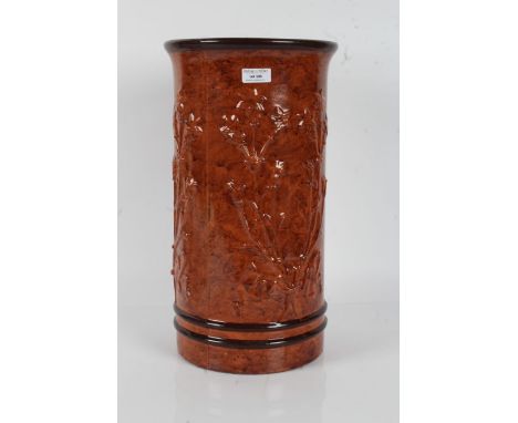 Brown glazed pottery stick stand, moulded with flowers and having running glaze, 43cm tall