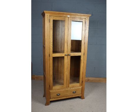 Light oak and glazed bookcase, the pair of glazed doors enclosing adjustable shelves, fitted single drawer below, 185cm tall 
