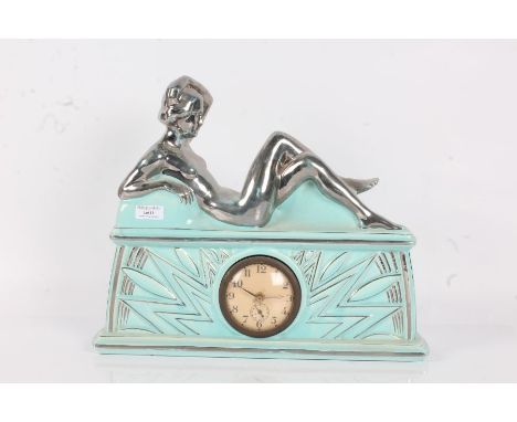 French Art Deco mantel clock, mounted with a silvered reclining lady above sunburst decoration on turquoise ground, 42cm wide