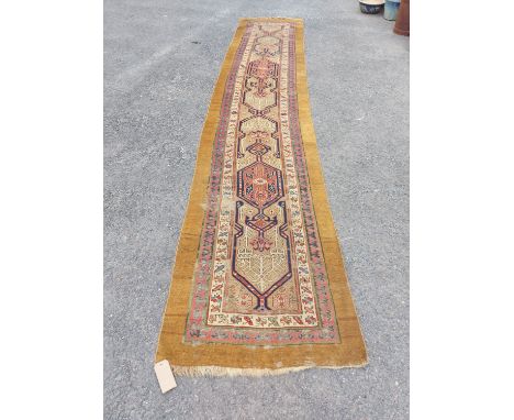 An antique Persian handmade wool runner with a gold ground - 4.64m x 93cm - worn condition