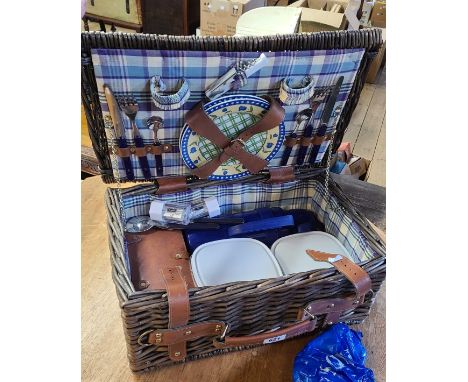 A wicker picnic hamper with contents