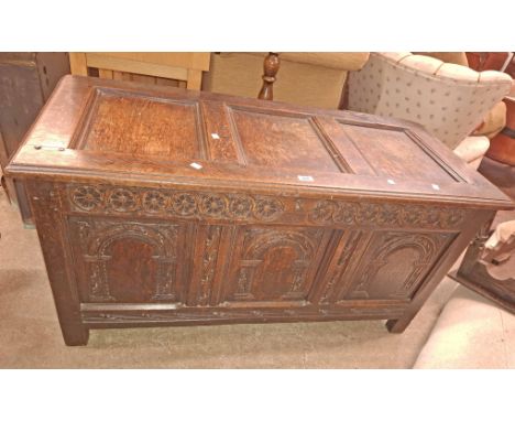 A 1.25m antique oak coffer with carved decoration to the triple panel front, internal candle box and iron strap hinges, set o