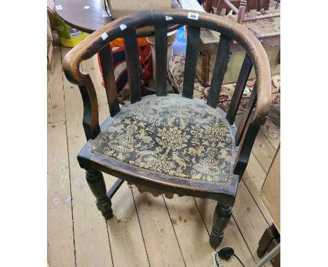 An antique stained oak framed bow back elbow chair with studded decorative tapestry seat panel, set on turned supports