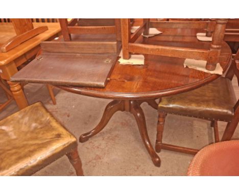 A Brights of Nettlebed style reproduction oak circular dining table with extra leaf, set on turned pillar and quadruple splay