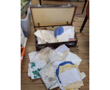 A leather suitcase containing antique textiles including embroidered tablecloths, lace doilies, etc.