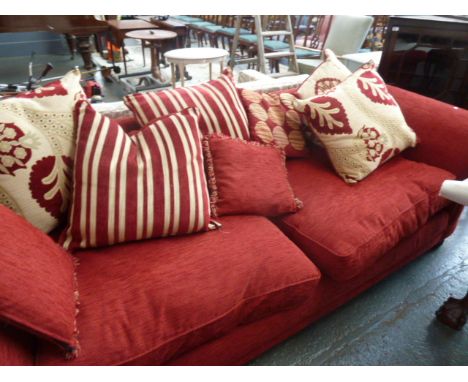 A large modern three seater sofa with 8 cushions upholstered in red fabric, 250cm wide